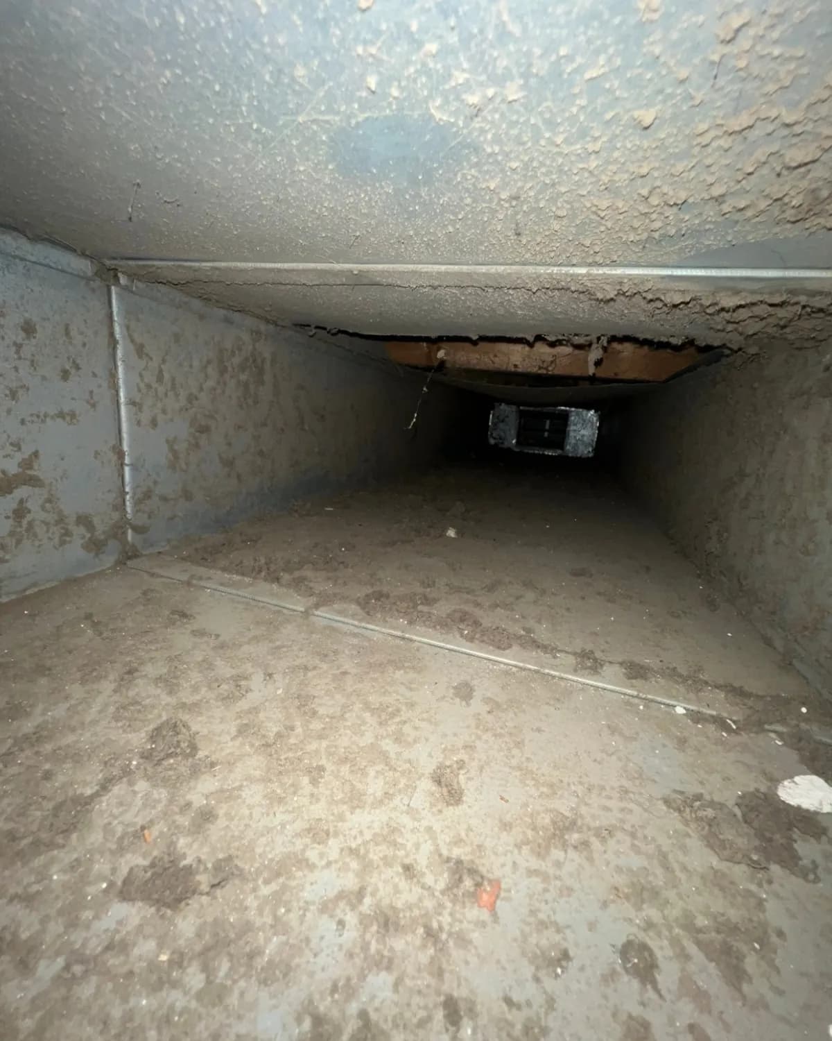 Main supply trunk-line interior coated with dust and debris before cleaning